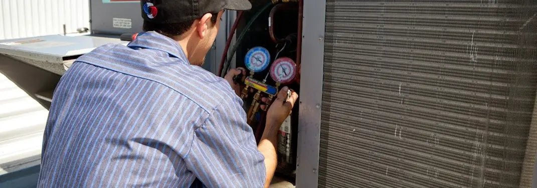 HVAC technician servicing a condenser unit in Milford